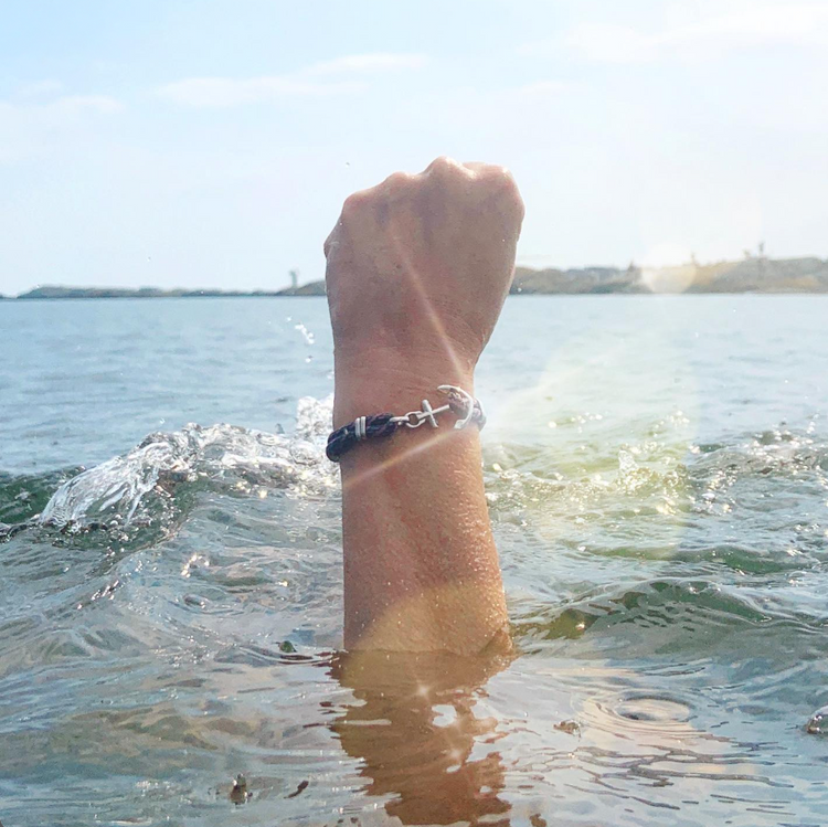 Raised fist above the sea wearing a Maris Sal anchor bracelet